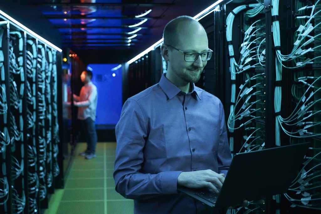 Professor Friederich arbeitet im Serverraum an einem Laptop.